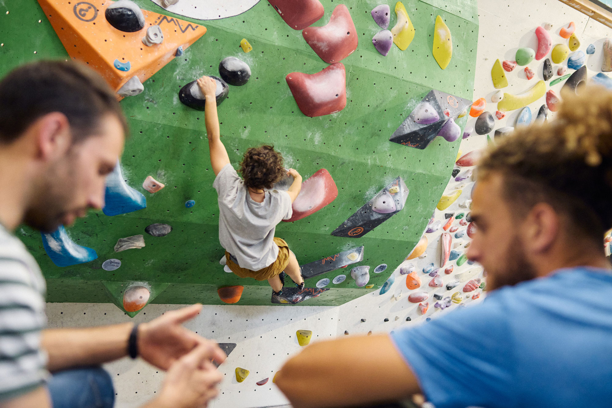 Un istruttore d consigli di arrampicata d un ragazzo mentre sullo sfondo un climber scala la parete